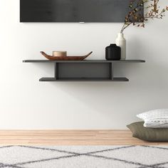 a black and white painting on the wall above a shelf with a bowl, vase and plate