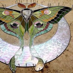 a stained glass piece with a butterfly on it's wings and two eyes in the center