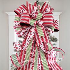 a red and green christmas wreath with polka dots, bows and candy canes hanging on the front door