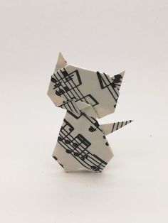 an origami cat with musical notes on it's body and tail, sitting in front of a white background