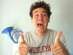 a young man making thumbs up while sitting in front of a laptop computer with his mouth open