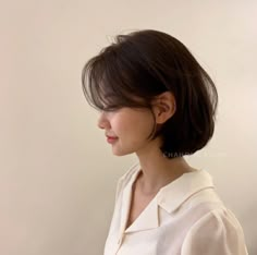 a woman with short hair wearing a white shirt and looking off to the side in profile