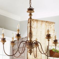 a chandelier with five lights hanging from it's center and an old door in the background