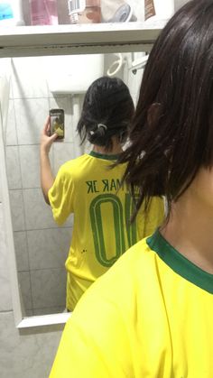 a woman taking a selfie in front of a mirror while wearing a yellow shirt