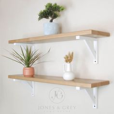 two wooden shelves with plants on them against a white wall in a home decor setting