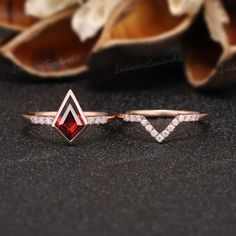 a diamond and red stone ring sitting on top of a black surface next to flowers