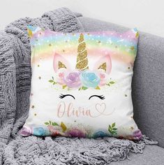 a unicorn pillow on a couch with the name aurora written in gold glitter and flowers