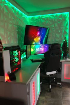 two computer monitors sitting on top of a desk in front of a green screen wall