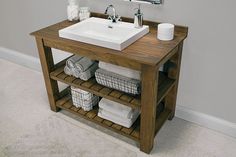 a bathroom sink sitting under a mirror on top of a wooden shelf with baskets underneath it