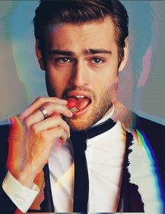 a man in a tuxedo eating a strawberry while wearing a ring on his finger