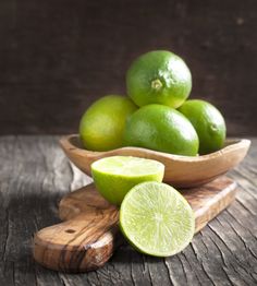 limes are in a wooden bowl on a table