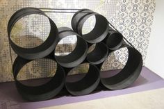 there is a sculpture made out of black paper circles on the floor in front of a wall