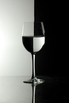 a glass of wine sitting on top of a table next to a black and white wall