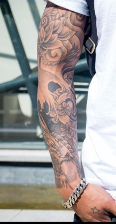 a man with a tattoo on his arm holding onto a skateboard in front of a building