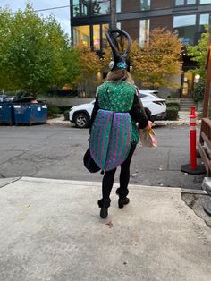 a woman walking down the sidewalk with an odd costume on