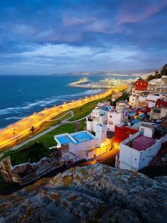 an aerial view of the beach and ocean at dusk, with buildings lit up in bright lights