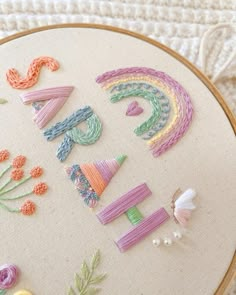 a close up of a embroidery on a hoop with flowers and letters written in it