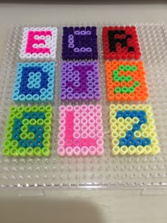 the letters and numbers are made out of legos on a clear plastic tray with beads