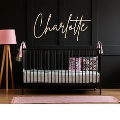 a baby crib in front of a black wall with the word charlotte on it