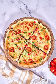 a pizza sitting on top of a wooden cutting board next to some tomatoes and cheese