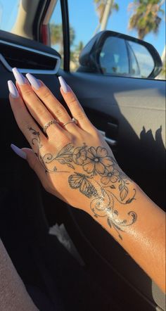 a woman's hand with flowers on her left wrist and tattoos on her right arm