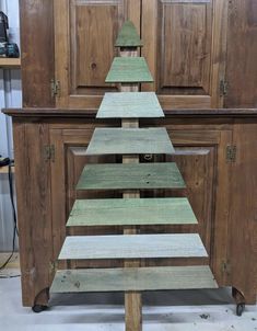 a wooden christmas tree sitting on top of a table next to a cabinet with drawers