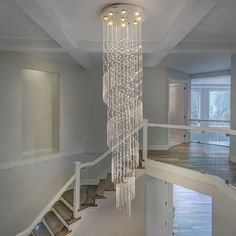 a chandelier hanging from the ceiling in a large room with white walls and stairs