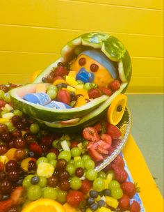 there is a bowl full of fruit with a bear in the center and another bowl filled with grapes