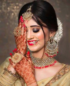 a woman with her hands on her face wearing jewelry and holding her hand up to her face