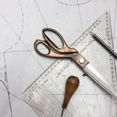 a pair of scissors sitting on top of a piece of paper next to a ruler