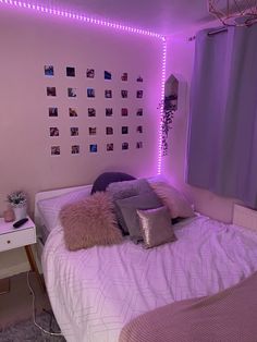 a bedroom with purple lights and pillows on the bed, along with pictures on the wall