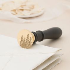 a rubber stamp with trees on it sitting on top of napkins next to a white plate