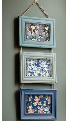 three framed pictures hanging on a wall with clothes pins attached to the frame and flowers in them