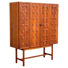 a wooden cabinet with four doors and three legs