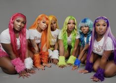 the girls are all wearing colorful wigs and posing in front of a gray background