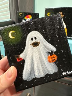 a hand holding up a halloween card with a ghost on it