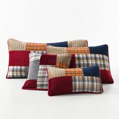 four different colored pillows on a white surface