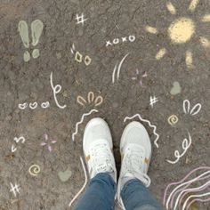 someone is standing on the sidewalk with their feet up and painted designs in the ground