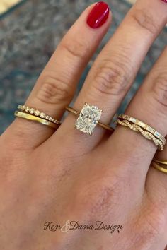 a woman's hand with three different rings on her fingers and one is wearing a red manicure