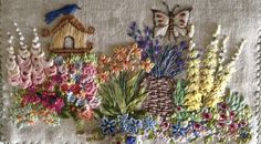 a bunch of flowers that are on top of a table cloth with some kind of birdhouse in the background