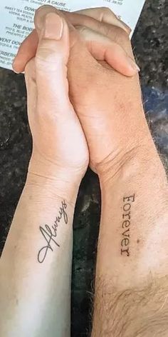 two people holding each other's hands with tattoos on their arms and the words together