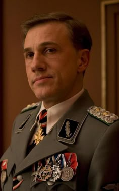 a man in an army uniform looks at the camera while wearing medals on his chest