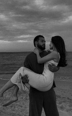 a man holding a woman on the beach