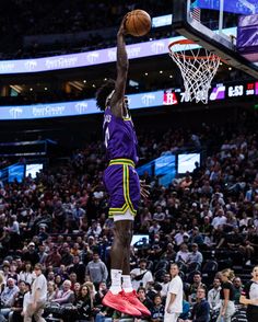 a basketball player dunking the ball in front of an audience at a sporting event