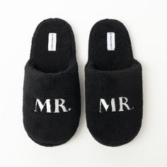 black slippers with mr and mrs written on the front in white letters, sitting on a white surface