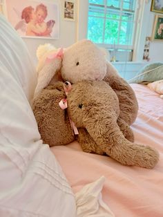 two stuffed animals sitting on top of a bed