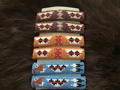 four bracelets with different designs on them sitting on a fur surface next to each other