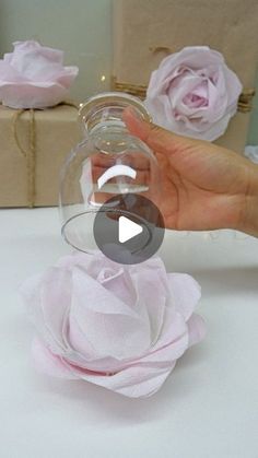 a person is holding a wine glass in front of some pink paper flowers and boxes