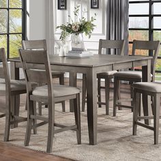 a dining room table and chairs in front of a window with an area rug on the floor