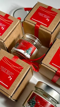 four christmas candles in boxes with ribbon around them